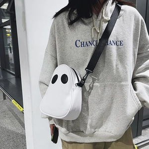 Detail shot of the ghost-shaped crossbody bag featuring contrasting black eyes and strap
