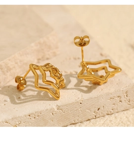 Macro view of gold-colored spider web pentagram stud earrings on stone texture
