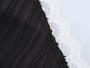 Détail du tissu en maille côtelée noire avec bordure en dentelle blanche délicate