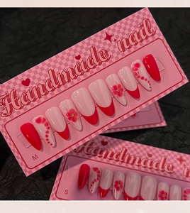 Detailed view of handmade long almond press-on nails with red French floral patterns