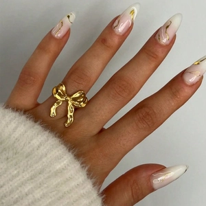 Bague ouverte élégante en forme de nœud doré pour femme portée par un mannequin sur blanc