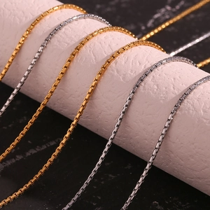 Classic 18K gold and silver stainless steel box chains displayed on white stone props