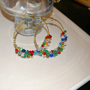 Close-up of golden hoop earrings featuring vibrant multi-color crystal beads and pearls