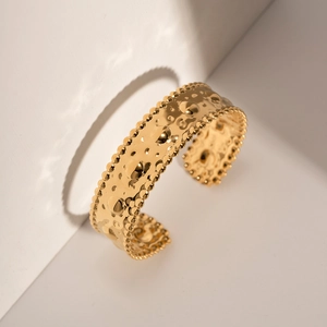 Detailed view of gold stainless steel bangle with hammered texture and beaded edges