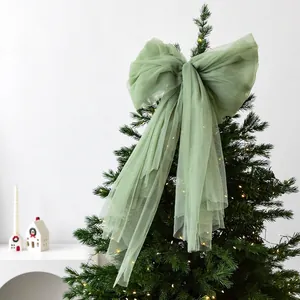 Sage green sheer mesh bow topper on a lit Christmas tree for festive home decor