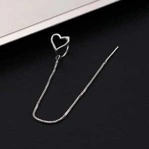 Macro detail of silver heart ear cuff with long tassel chain on black leather background