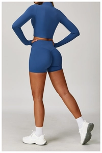 Detail of navy high-waist fitness shorts and long sleeve cropped top on a studio model