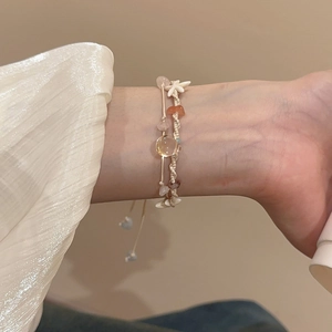 Detail eines Perlenarmbands mit Naturstein und Seestern-Anhänger am Handgelenk