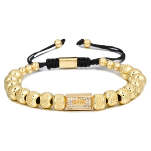 Detail of gold beaded bracelet with crown charm and adjustable black woven cord