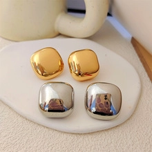 Minimalist metallic square hoop earrings in polished gold and silver finishes on a stone base