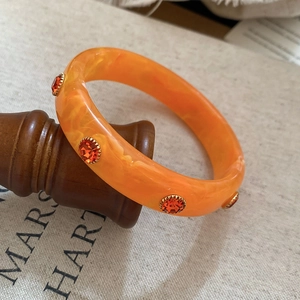 Macro shot of orange marble resin bracelet with rhinestone detailing and vintage texture