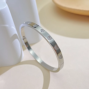Detailed close-up of silver heart-shaped bangle with inlaid diamonds and flat design