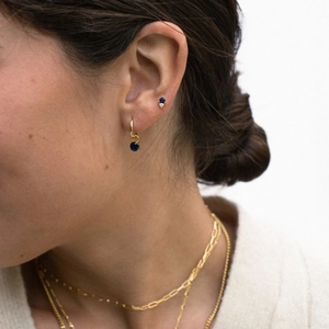 Primer plano de aros dorados con colgantes de piedras azules y pendientes a juego