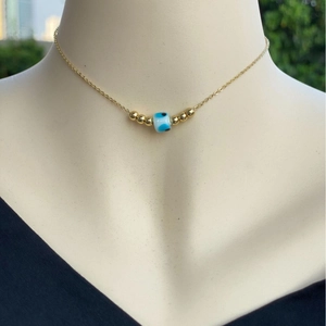 Collana placcata oro 18 carati con perla malocchio e grani dorati indossata da un modello