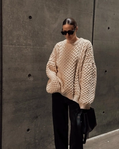 Détail de la texture en maille torsadée épaisse et du tissu beige du pull oversize