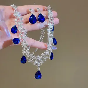Elegant silver-toned jewelry set with pear-cut blue stones and floral diamond accents