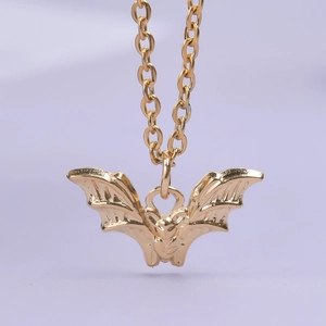Detailed close-up of a golden 18K stainless steel bat pendant with intricate wing texture
