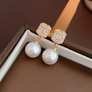 Detailed macro of gold plated earrings featuring zircon stones and round white pearls