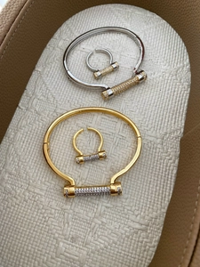 Close-up of paved diamond horseshoe bangle and ring set on a premium textured display