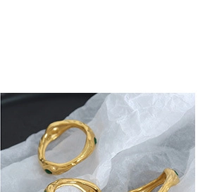 Detailed close-up of gold-plated rings featuring irregular molten texture and green gems