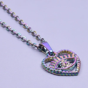 Macro shot of 18k gold plated rainbow heart eye pendant on a stainless steel chain