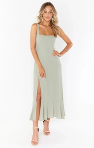 Detail of sage green midi dress featuring a square neckline and high side slit with ruffles