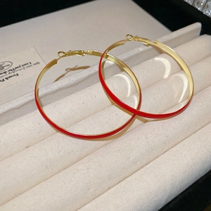 Close-up of golden round hoop earrings with elegant red enamel coating and metallic luster