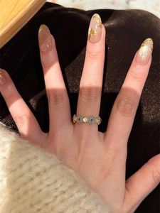 Detail of 18k gold plated floral ring with blue petals and zircons on a model finger