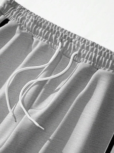 Close-up of gray melange joggers featuring an elastic waistband and white drawstrings