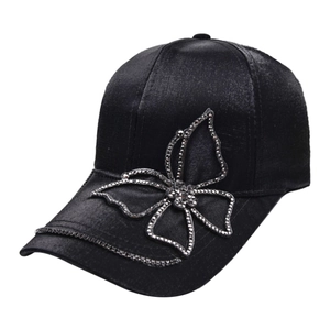 Detailed view of black satin baseball cap with rhinestone butterfly and jeweled brim
