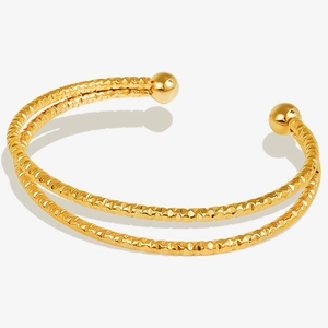 Detail shot of the textured diamond-cut surface and smooth gold beads of this open bangle