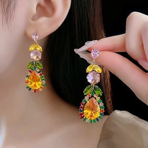 Close-up of leaf-shaped drop earrings with vibrant yellow, pink, and green zircon stones