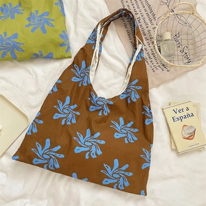 Artistic blue floral canvas tote bag on white bedding with books and vintage decor