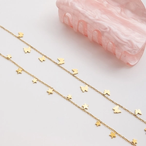 Detail view of 18K gold star and butterfly charms on a polished stainless steel necklace