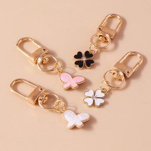 Detailed view of enamel clover and butterfly keychains with rhinestones and gold plating