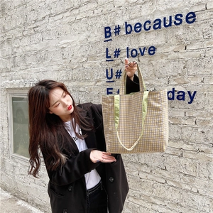 Bolso tote de lona a cuadros vintage con asas verde claro en una toma de calle al aire libre