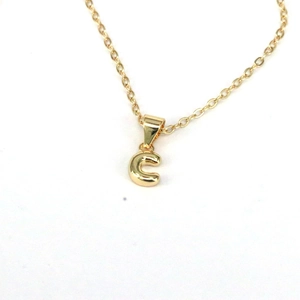 Detail view of a minimalist golden letter C pendant necklace on a clean white background