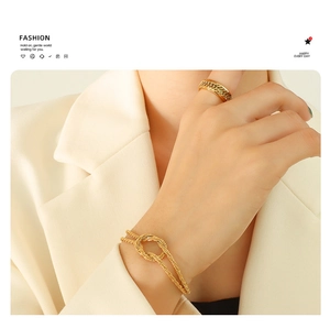 Close-up of a gold knot bracelet and textured chain ring on a female model