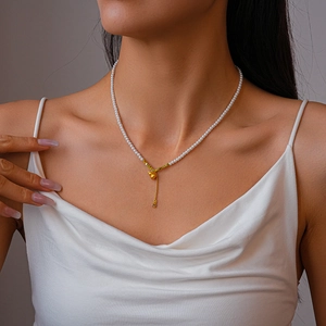 Gros plan d'un collier de perles vintage avec pendentif gourde dorée sur un mannequin