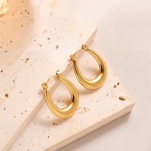 Gros plan de boucles d'oreilles en titane doré 18k en forme de U sur support en pierre