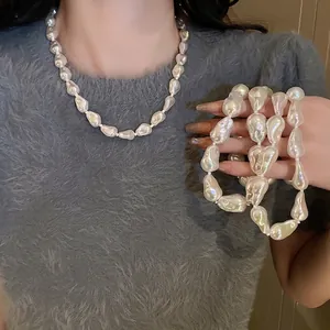 Elegant Baroque pearl necklace with irregular white pearls worn on a grey knit sweater