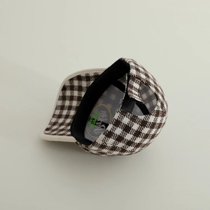 Detail of brown plaid pattern and adjustable strap on children winter baseball cap