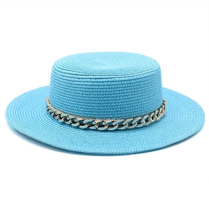 Macro shot of bright blue straw boater hat featuring a thick gold chain decoration