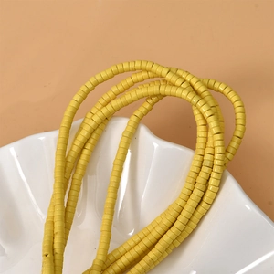 Strands of yellow 2x4mm cylinder turquoise spacer beads in a white shell bowl for jewelry DIY