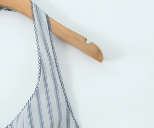 Detailed view of blue striped fabric with elegant wavy lace trim on the neckline