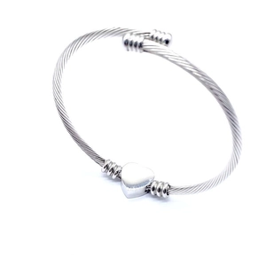 Detailed macro view of silver cable wire bangle featuring a polished heart-shaped metal charm