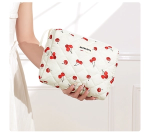 Quilted cotton makeup bag featuring red cherry prints and an elegant brand tag