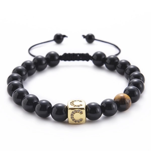 Macro detail of black onyx and tiger eye stone beads bracelet with micro-pave letter C