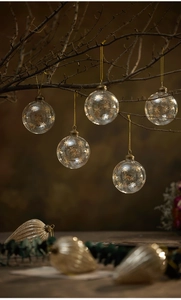 Detail of clear glass Christmas ornaments with gold snowflake patterns and hanging strings