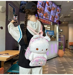 Rear view of a white plush bunny backpack with pink printed straps on a model